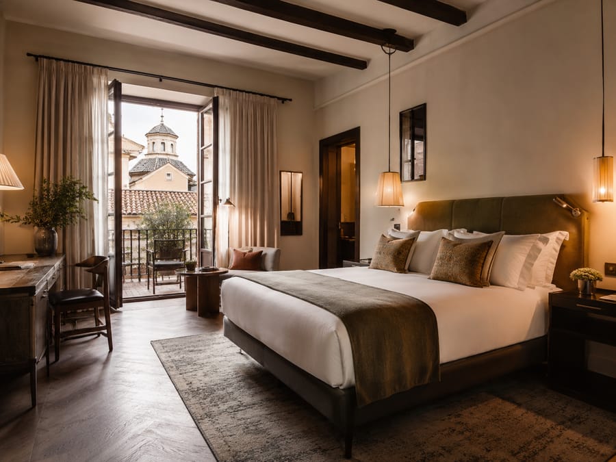 Habitación de hotel boutique con vigas de madera y balcón a un casco histórico