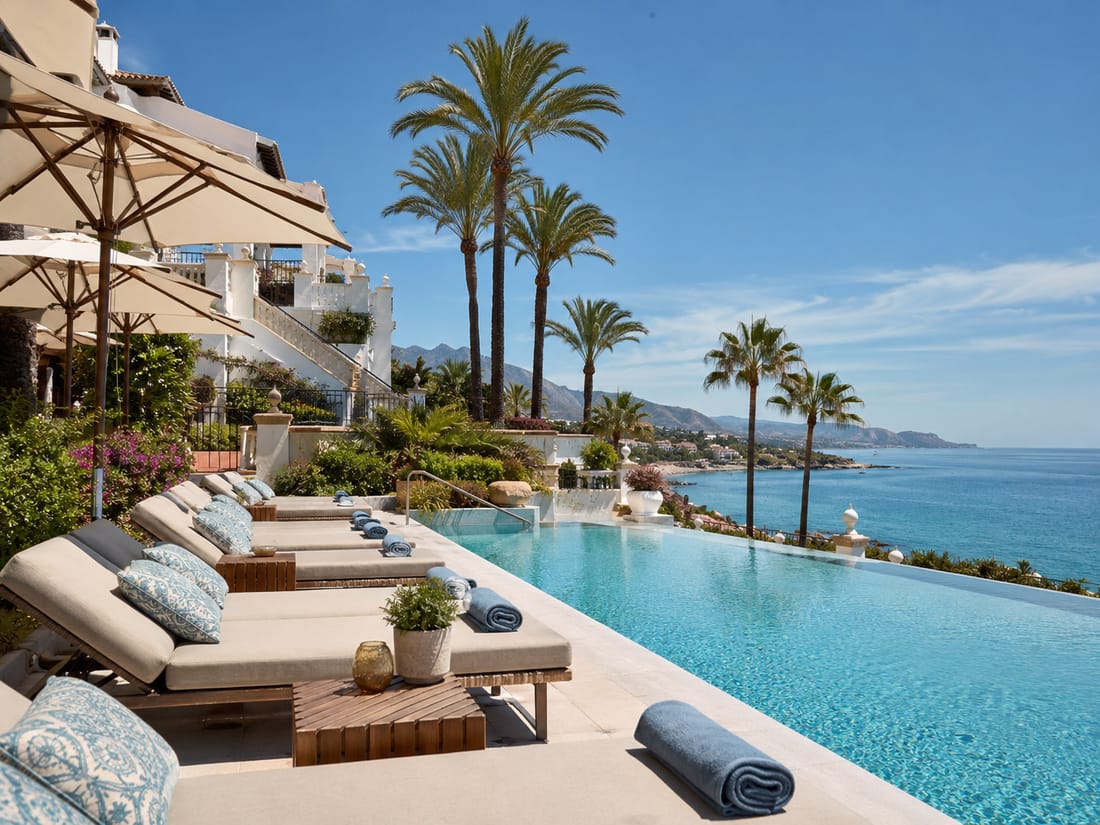 Piscina de un hotel en la costa mediterránea con palmeras y vistas al mar